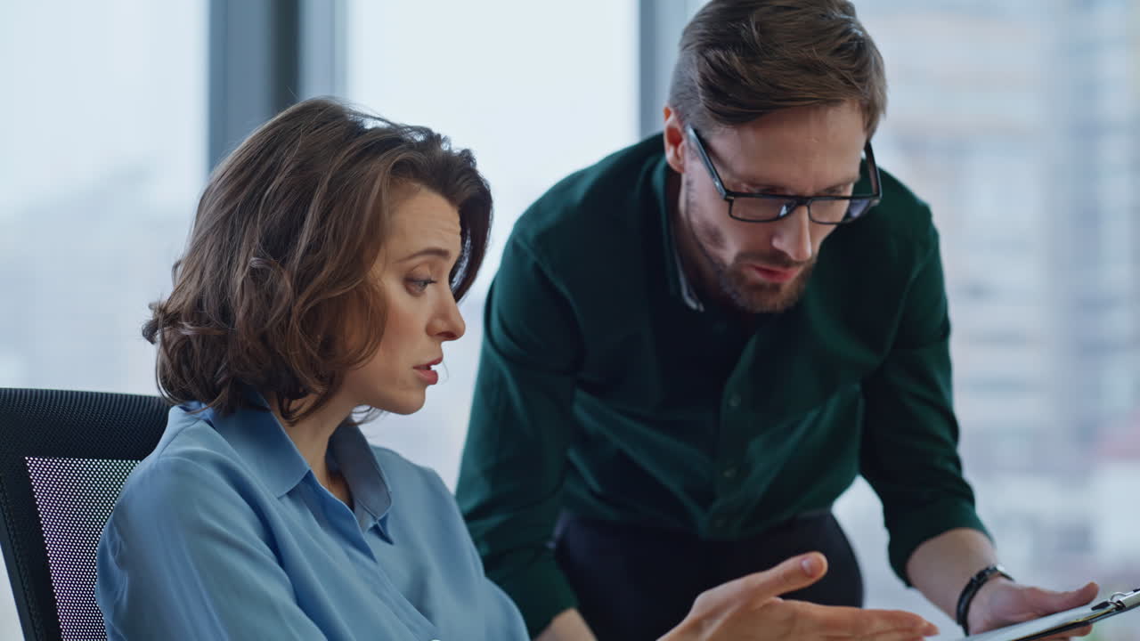 Executive explaining financial data in documents to woman manager at workplace