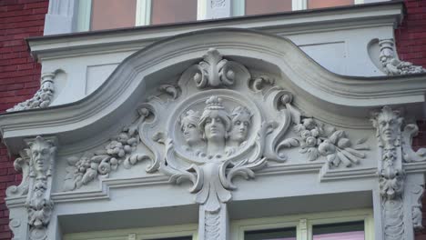 plaster relief doorframe sculptural woman with a wine grapes three pillars with greek gods red brick wall around windows frame mid close up decoration outdoor cloudy shady details