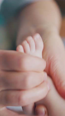 professional pediatrician holds newborn baby leg and practices hypertonus massage on feet and toes extreme close view