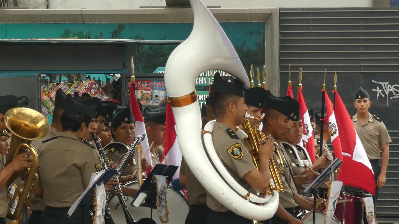 A marching band made of Peruvian policemen and women. Some hold Peruvian flags, one holds a big tuba, others drums and more instruments.