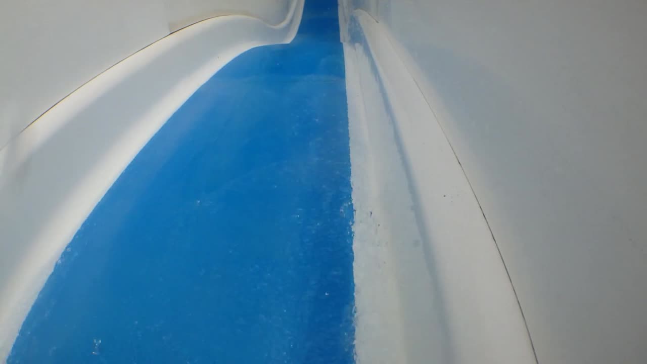 toma de acción en primera persona en cámara lenta de un hombre bajando por un tobogán de agua en un parque de diversiones acuático