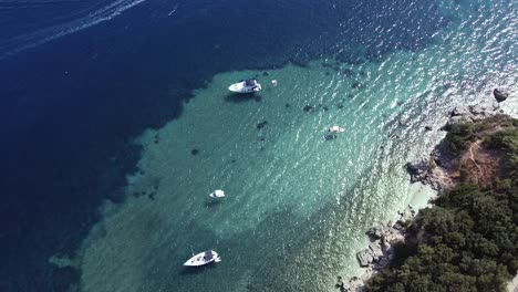 Toma-Aérea-De-Botes-Flotantes,-Agua-Azul-Clara,-Pequeñas-Olas-Y-Pequeña-Isla