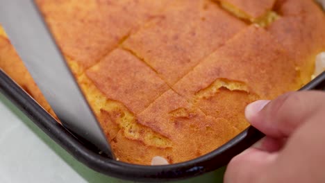 cortando la tarta de maíz en la bandeja de horneado mira de cerca