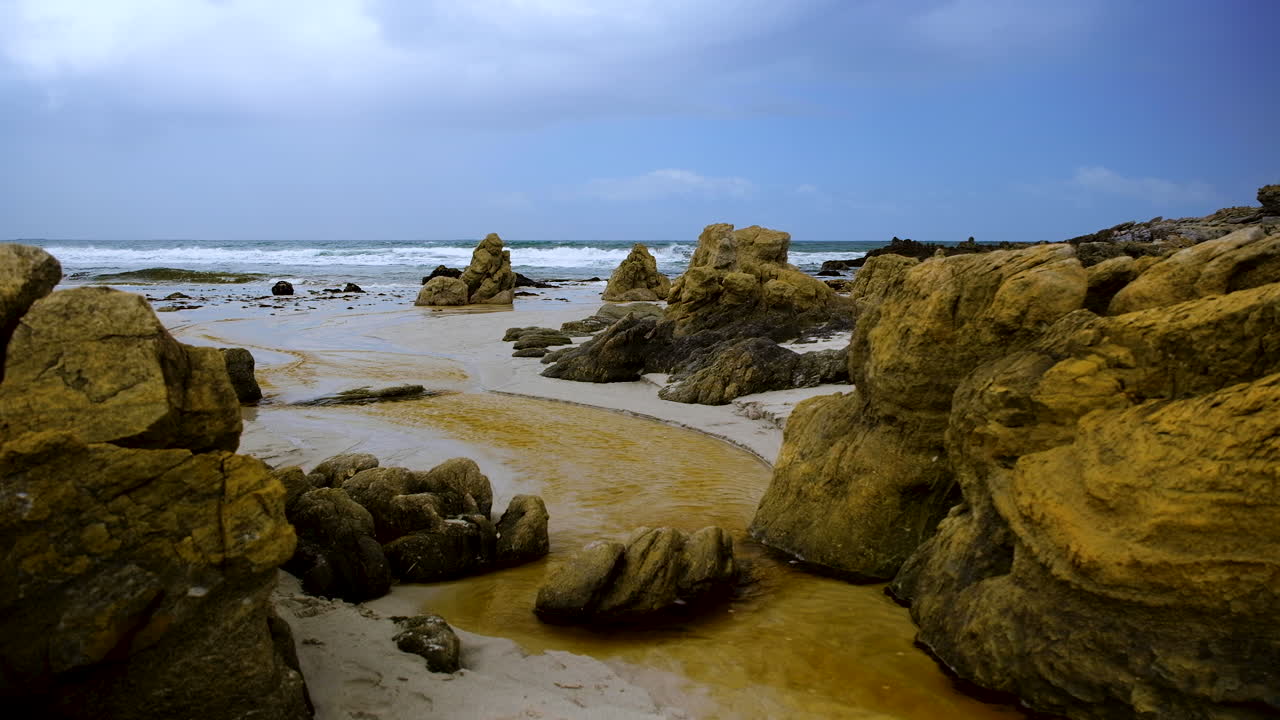 el agua de la laguna rica en taninos fluye a través de las rocas costeras en la playa hacia el océano