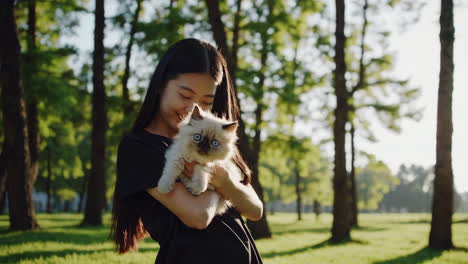 young woman holding a cute kitten in a park