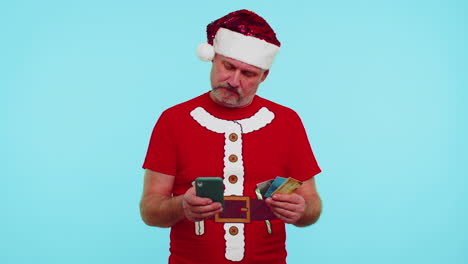 Man-in-Christmas-t-shirt-using-credit-bank-card,-smartphone-while-transferring-money-shopping-online