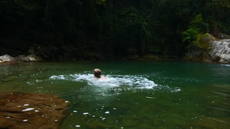 person jumping into crystal-clear river in a forest