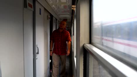 un hombre camina por el vagón de tren y entra en el compartimento