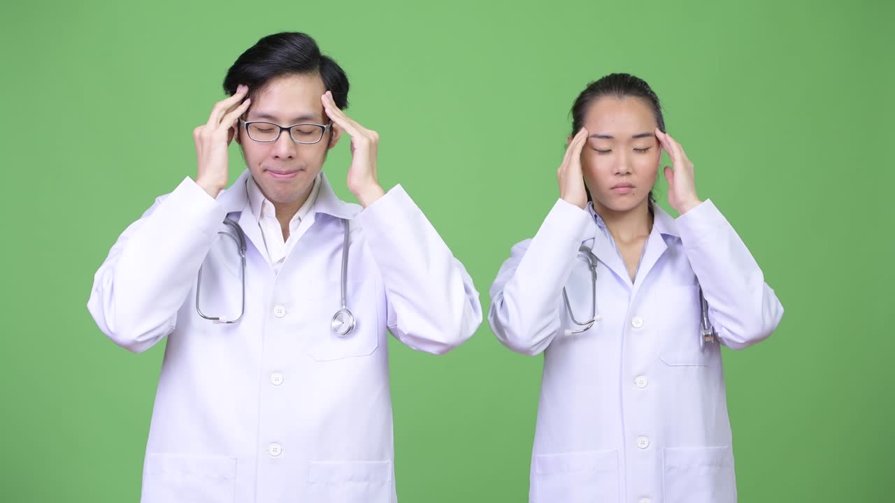 Young Asian couple doctors having headache together