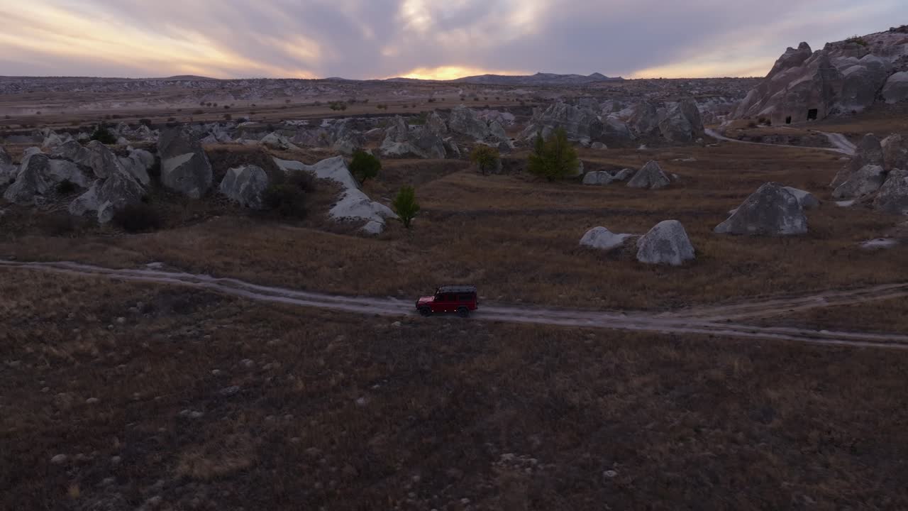 Spedizione di veicoli fuoristrada attraverso la valle rocciosa sotto il bagliore del tramonto