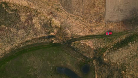 aerial shots of the landscape, overhead perspective over a red car parked in a spring meadow