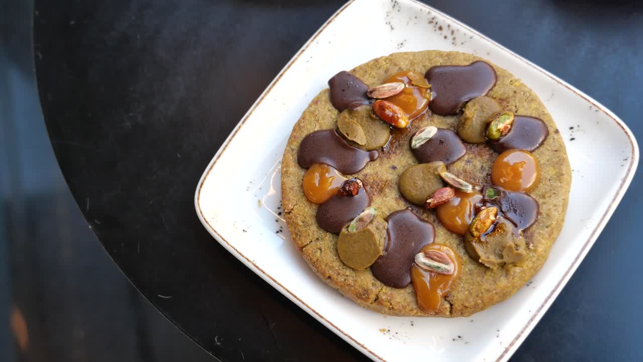Close-up of a dessert with chocolate, caramel, and nuts being held