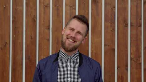 hombre sonriente frente a la pared de madera
