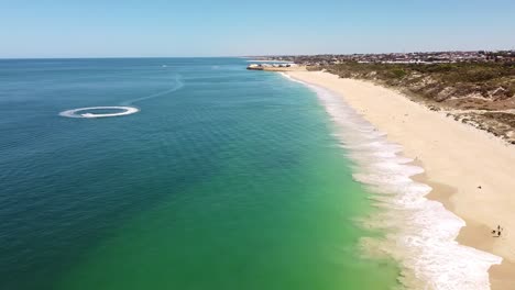 Aerial-view-over-beach-with-jetski-racing-around-in-circles-leaving-wake-patterns