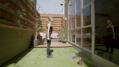 Una-Mujer-Blanca-Haciendo-Sentadillas-En-Su-Patio-Trasero-Frente-A-Su-Computadora