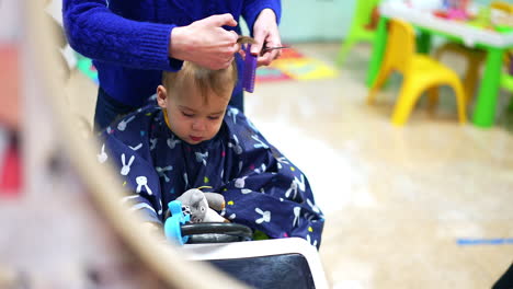 mother giving a haircut to her baby