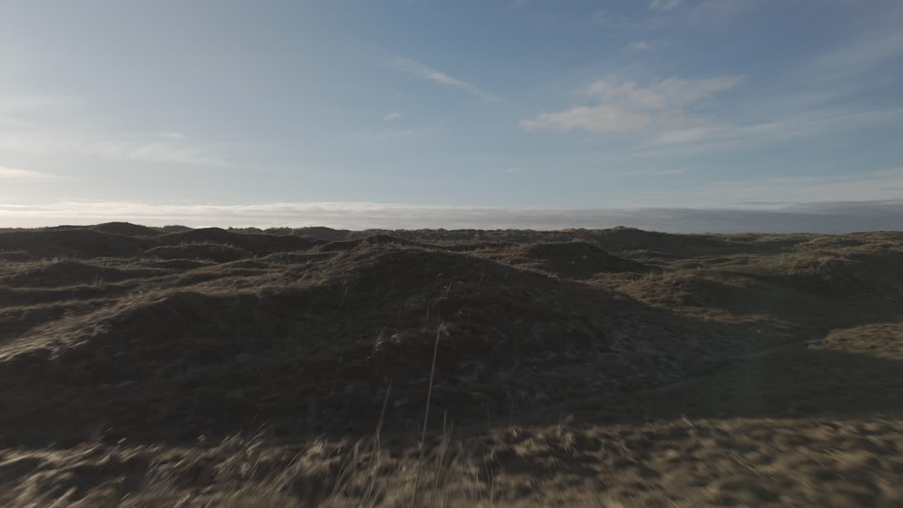 Fast flying drone shot over the dunes near Borestranda Norway during sunset going towards the beach and sea and flying over the waves LOG