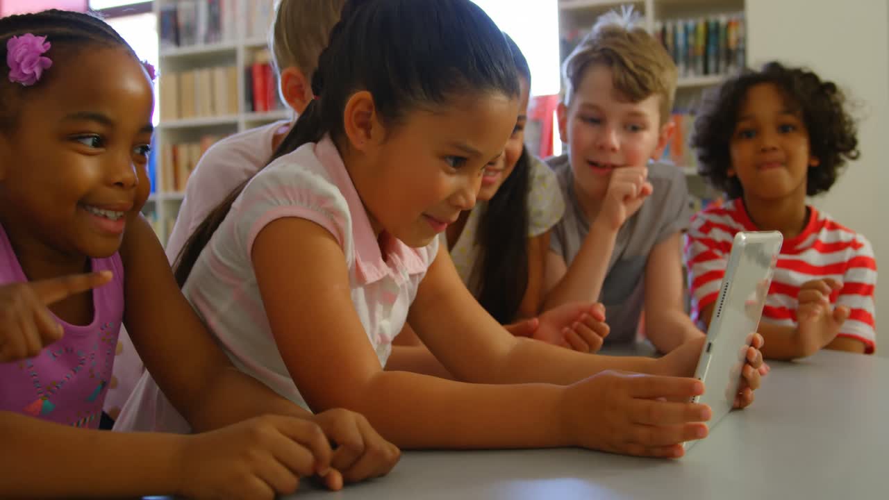 Group of diverse group of schoolkids studying together on digital tablet at table 4k