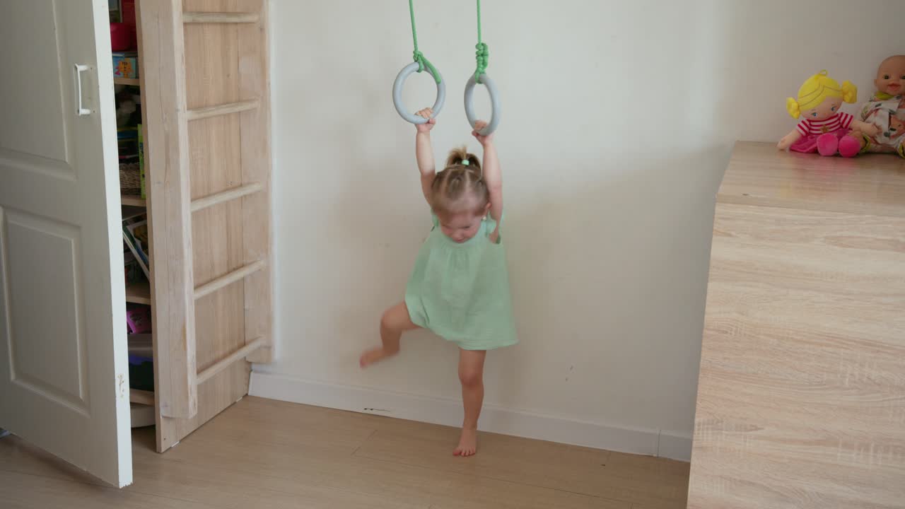 Bambina felice che gioca agli anelli da ginnastica al chiuso