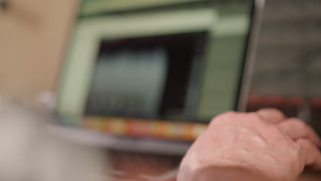 a close-up shot of a hand with a very blurred background, which appears to include professional audio production equipment. the focus is on the hand, while the background hints at a creative workspace