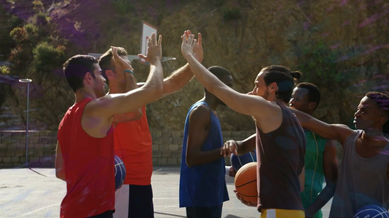 Basketball players forming drill huddle, raising hands, breaking, purple haze drifting over group