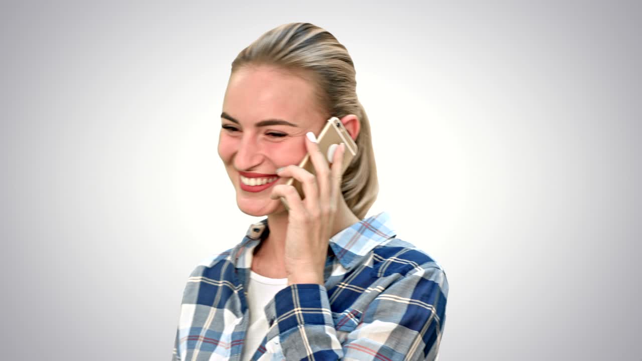 Bella donna in abiti casual che parla al telefono e sorride su sfondo bianco.