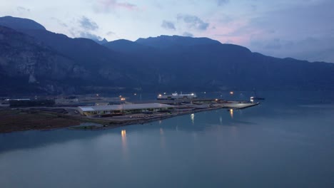 aerial view of squamish spit conservation area harbour illuminated at night, drone fly above stunning sunset seascape