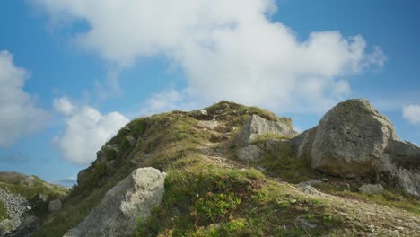 4K-Cinematic-shot-of-a-coastal-foot-path-going-up-a-hill-to-the-edge-of-a-cliff,-on-a-sunny-day,-on-the-island-of-Portland,-in-Dorset,-England