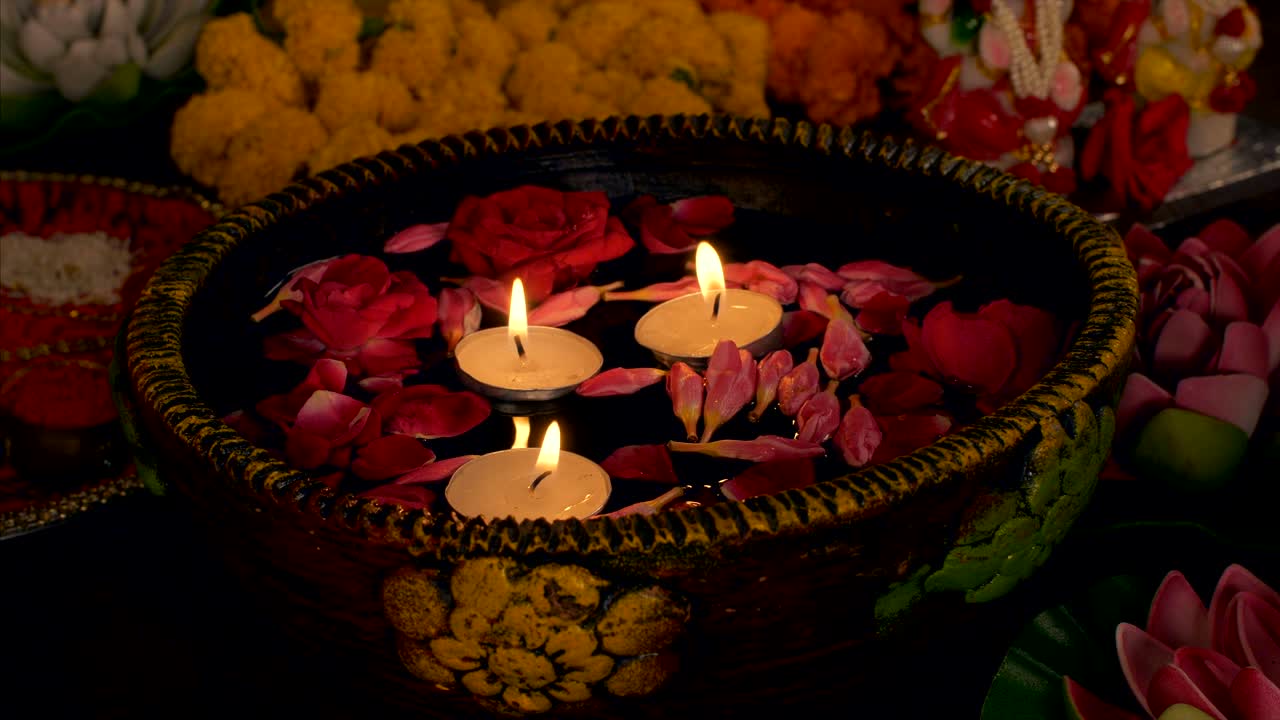 Women placing floating candles / diyas in a bowl for diwali festival