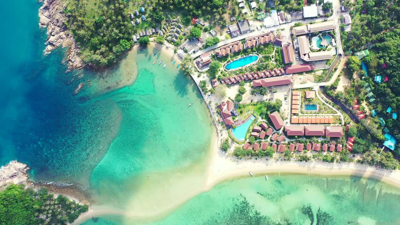 Beautiful luxurious vacations resort with villas and pools in front of calm turquoise lagoon surrounded by palm trees, Koh ma, Thailand