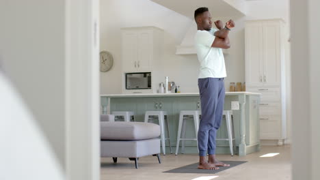 focused african american man stretching in sunny living room, slow motion