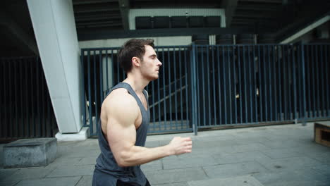Close-up-male-runner-jogging-on-outdoor-workout.-Side-view-of-running-man.