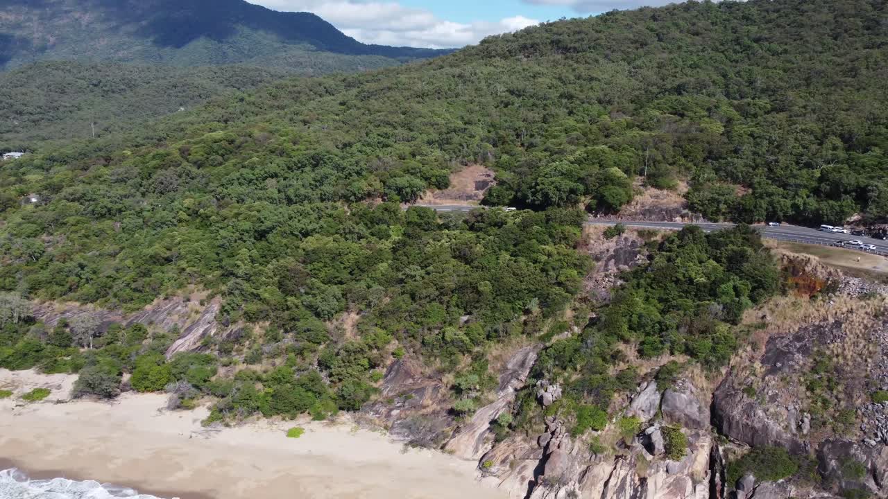 4K aerial video of a rugged coastline and some sandy beach with mountains in the background