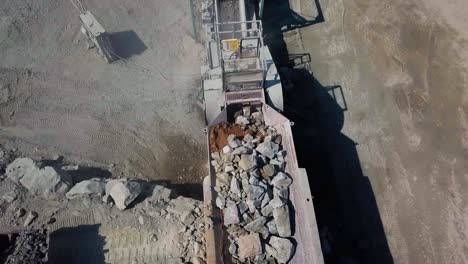 large rocks being fed into stone crusher machine to make smaller rock and gravel