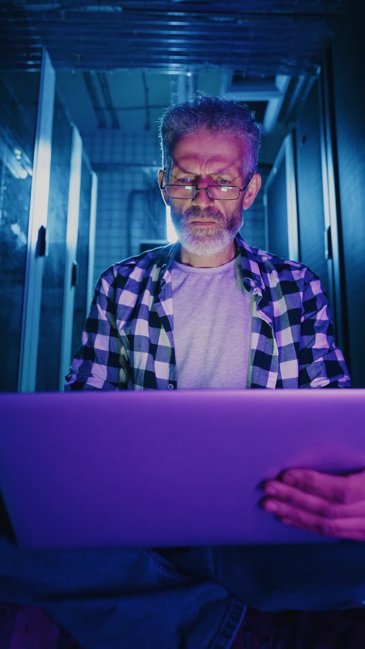 Man Working on a Laptop in a Server Room