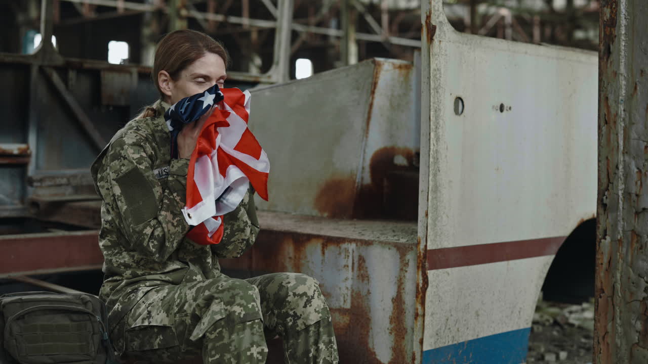 A soldier mourning with the American flag in a desolate factory