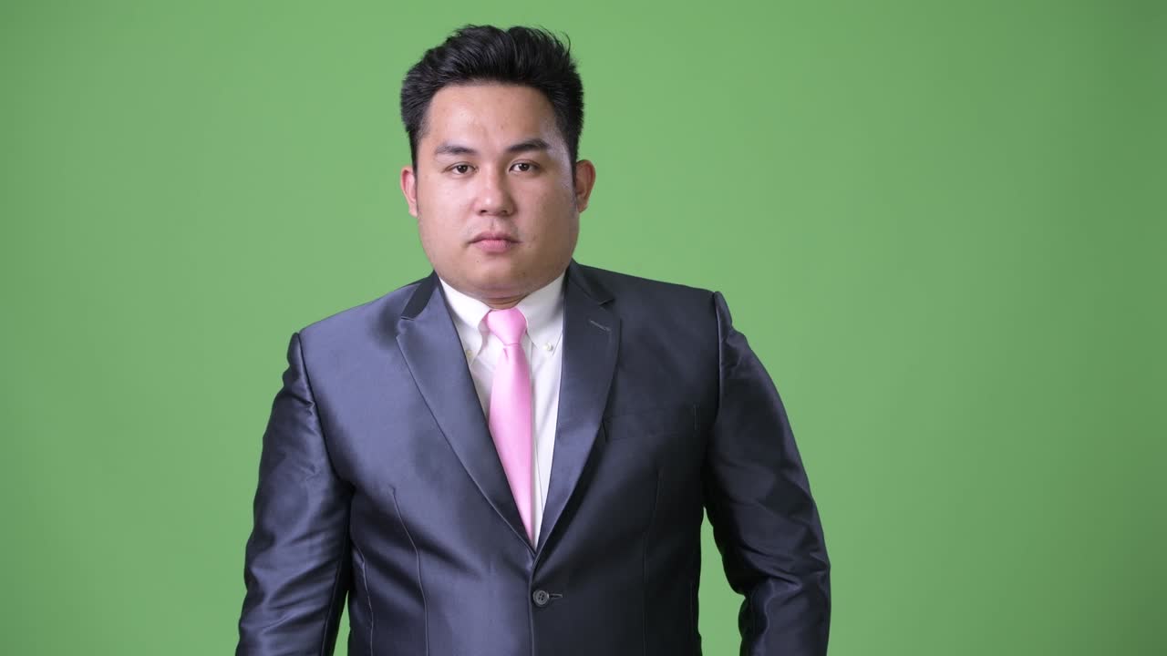 초록색 배경에 젊은 잘생긴 과체중 아시아 사업가