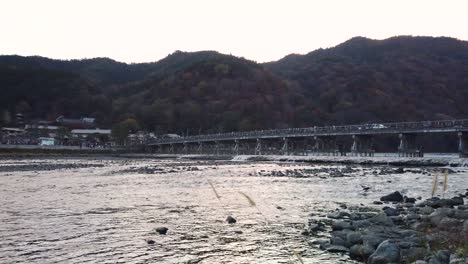 togetsukyo bridge, slow motion pan as sun sets over arashiyama in kyoto, japan