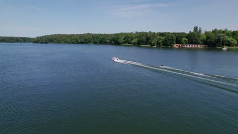 motorboat pulling waterski on a lake in the forest, drone shot