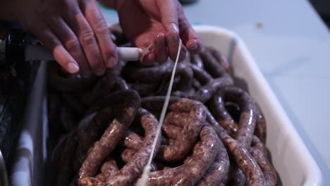 sliding hog casing to the tube of a sausage stuffer machine - stuffing sausage - close up