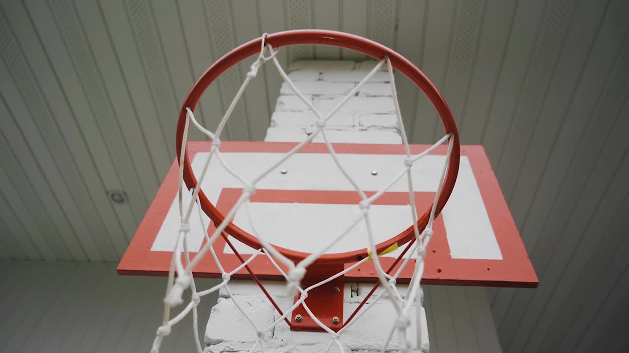 A basketball net hangs on the wall in the courtyard of a private house.