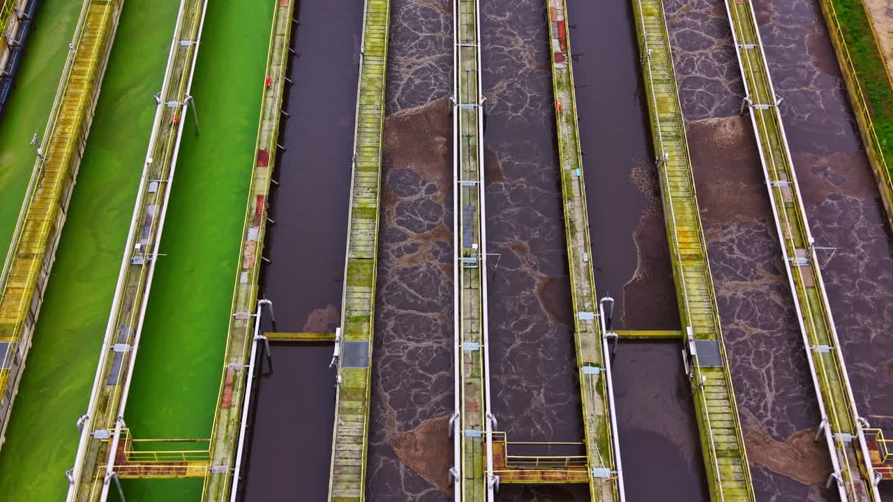 Wastewater treatment facility shows various stages of water purification in a large industrial area during daylight