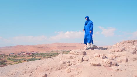 man in blue traditional clothing in moroccan desert landscape