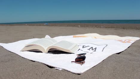 open book on a towel lying on a sunny beach 1