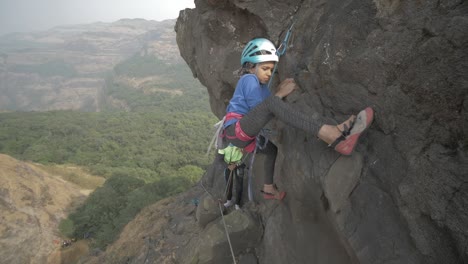 a young indian girl attempting to rock climb a beautiful pinnacle on sunny day