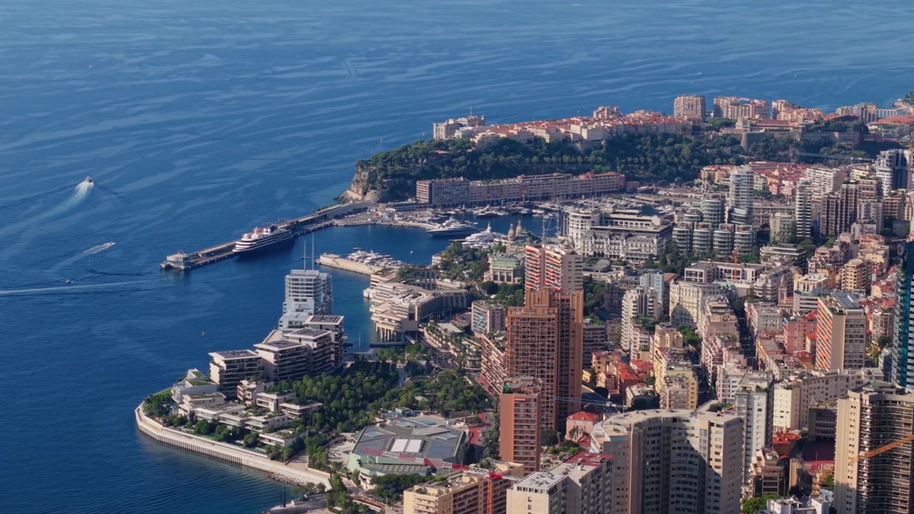 Veduta aerea della costa di Montecarlo con grattacieli e un porto turistico sotto la luce del sole.
