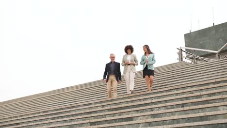 business people discussing while descending stairs in city