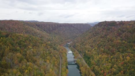 slow aerial dolly of cars driving along the river gorge bridge with autumnal trees