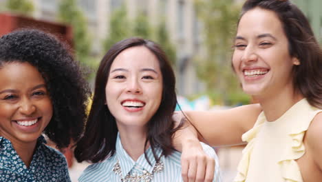 female colleagues smiling to camera outside their workplace