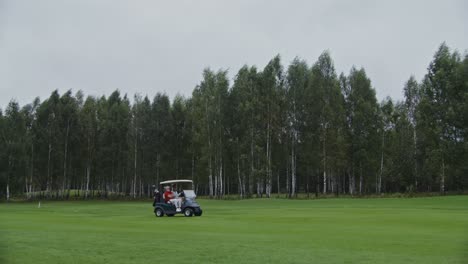 golfistas en un carro en un campo de golf con viento